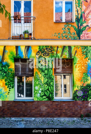 Berlin, Prenzlauerberg, Lychnener Straße. Farbenfrohe Gebäude mit Blumen bemalte Fassade enthält Wohnungen und Büros. Blick auf die Straße von mehrfamilienhaus Stockfoto