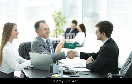 Handshake Geschäft Leute hinter einem Schreibtisch im Büro Stockfoto