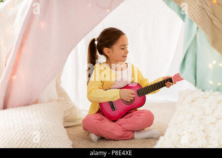 Mädchen spielen Spielzeug Gitarre im Kinder Zelt zu Hause Stockfoto