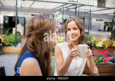 Glückliche junge Frauen trinken Kaffee im Café im Freien Stockfoto