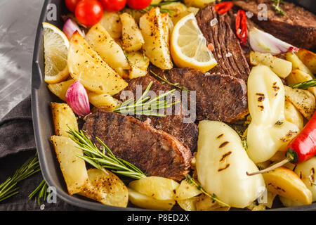 Rindersteaks vom Grill mit gebackenen Kartoffeln und Gemüse in einer Pfanne Grill, Makro. Stockfoto