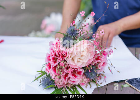 Männliche florist erstellen Schönen Blumenstrauß im Blumengeschäft. outdoor Arbeit im Blumenladen. Mann Assistant oder Eigentümer im floralen Design Studio, Dekorationen und Arrangements. Stockfoto