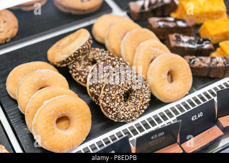 Donuts und Ringen. Warmes Gebäck liegen auf dem Regal im Cafe. Brötchen und Bagels im Store. Stockfoto