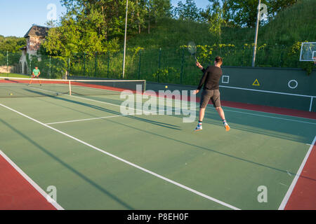 Man spielt Tennis auf dem Tennisplatz im Freien in den Sonnenuntergang. Stockfoto