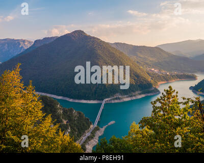 Fantastische Aussicht auf die Schlucht des Flusses Piva (Pivsko jezero) mit herrlichem, türkisfarbenem Wasser und die Brücke über den Fluss im Sommer abends, Montenegro Stockfoto