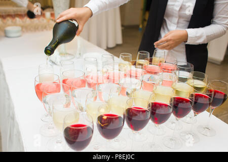 Kellner gießt Wein in die Gläser, viele Sorten von Getränken, Frühstücksbuffet Stockfoto