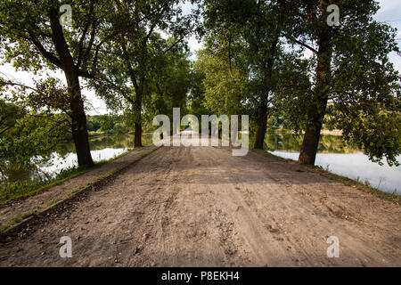 Village Road zwischen Seen und Bäume Stockfoto