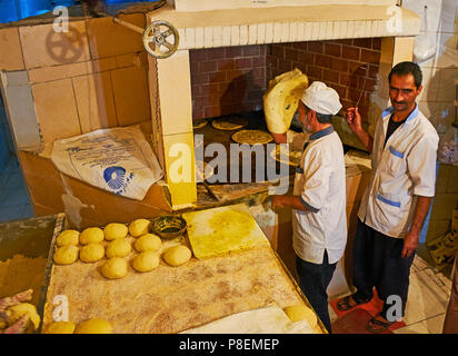 KERMAN, IRAN - 16. Oktober 2017: Die Bäcker bei der Arbeit, traditionelle Fladenbrot in einem grossen Ofen in der kleinen Bäckerei, am 16. Oktober in Kerman. Stockfoto