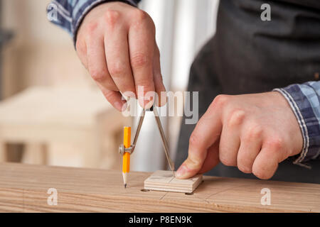 Eine Nahaufnahme eines männlichen Tischler Marken aus einem Metall Kompass und einen Bleistift auf eine Bar aus Holz für die Herstellung von Möbeln. Stockfoto