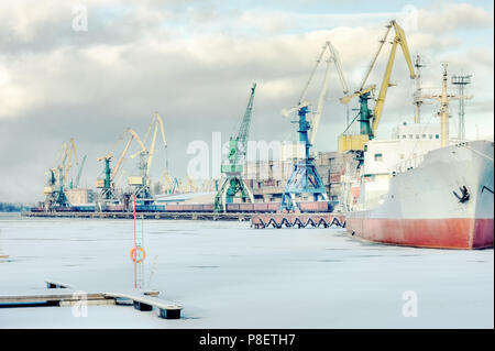 Cargo trade Port auf dem gefrorenen Fluss Daugava in Riga beim Entladen und Laden der Eisenbahnwagen Stockfoto