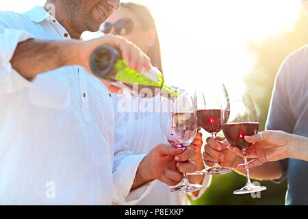 Menschen bei Wein Party im Freien. Weinfest. Man gießt Rotwein in der weingläser Stockfoto