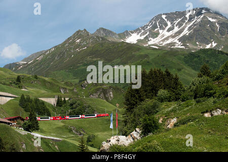 Andermatt im Kanton Uri, Schweiz, an denen Schweizer Berg Züge bis Klettern in Richtung Oberalppass und schweizer Fahnen. Juni 2018 Andermatt ist ein m Stockfoto