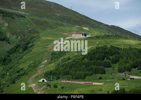 Andermatt im Kanton Uri, Schweiz, an denen Schweizer Berg Züge bis Klettern in Richtung Oberalppass und schweizer Fahnen. Juni 2018 Andermatt ist ein m Stockfoto