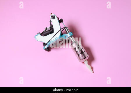 Eine blaue Classic Tattoo Maschine auf einem rosa Hintergrund Stockfoto