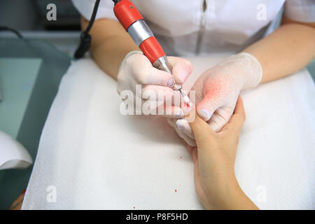 Maniküre in Prozess. Closeup Schoß einer Frau in einem Nagelstudio, Maniküre, durch eine Kosmetikerin mit Nagelfeile. Frau erhalten Nagel Maniküre. Stockfoto