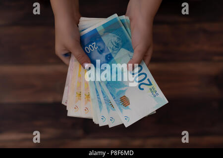 Konzept der zahlen Geld, zwei Hände der Kinder holding Israelischen Banknoten in 200 Schekel ILS Stockfoto