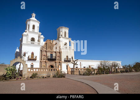 Weiß getünchten Türme und Mauern von San Xavier del Bac Mission in der Nähe von Tucson, Arizona, Kontrast mit Deep Blue Desert Skies. Verschiedene Kakteen wachsen neben Wand Stockfoto