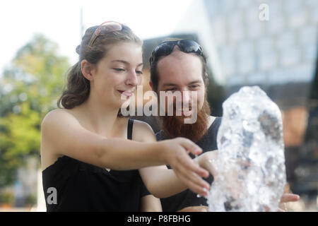 Paare, die ihre Hände in einem Springbrunnen Stockfoto