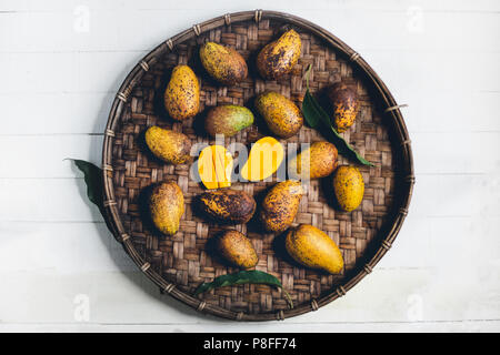 Natur mango Im dreschen Korb auf einem Holztisch und einem weißen Tuch Stockfoto