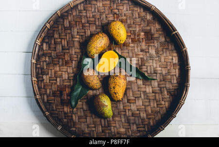 Natur mango Im dreschen Korb auf einem Holztisch und einem weißen Tuch Stockfoto