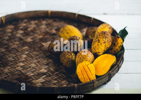 Natur mango Im dreschen Korb auf einem Holztisch und einem weißen Tuch Stockfoto