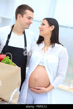 Mann und seine schwangere Frau sind Kämmen durch die Pack, stehen in der Küche Stockfoto