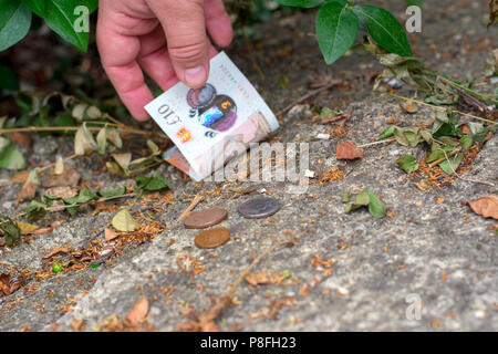 Abholung Geld vom Boden Stockfoto