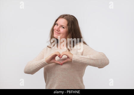 Portrait von lächelnden jungen Frau mit Herz Form Hand unterzeichnen. Sorgen um die Gesundheit. Kontrolle der Zuckergehalt. Stockfoto