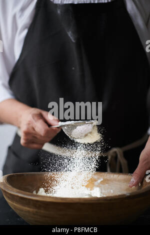 Weibliche Hände Mehl in Schüssel sieben. Stockfoto