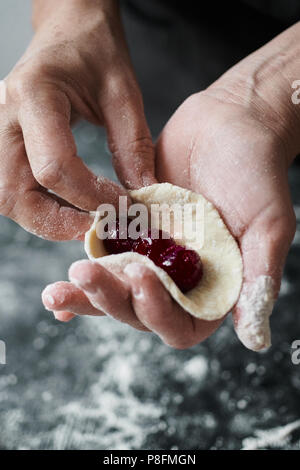 Frau Koch manuell formt Knödel mit Kirschen gefüllt Stockfoto