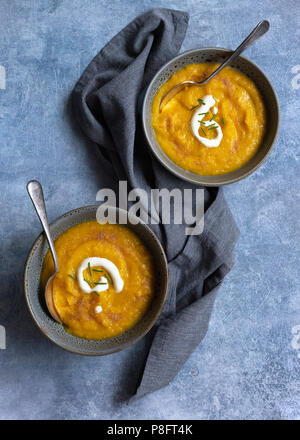 Zwei Schalen mit dicken Kürbis Suppe mit Löffeln auf einem blauen strukturierten Hintergrund. Stockfoto