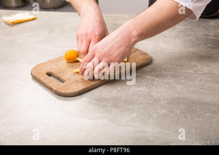 Männliche Hände, hausgemachte Knödel Gebäck Tortellini oder Ravioli. Modell für hausgemachte Nudeln mit Meeresfrüchten gefüllt Stockfoto