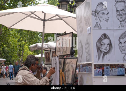 Ein street artist unter einem Sonnenschirm Zeichnung eine Karikatur Las Ramblas Barcelona Spanien Europa sitzen Stockfoto
