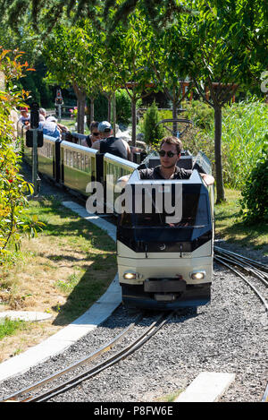 Ein Miniatur-Diesel-Elektrobahn Zug zieht Reisebusse bei der Schweizer Vapeur Parc Miniature Railway am Genfer See Le Bouveret Schweiz Stockfoto