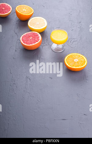 Zitrusfrüchte mit verschiedenen Schichten und Saft in ein Glas. Grauen Stein Hintergrund. Vitamine und Gesundheit in Essen. Platz kopieren Stockfoto
