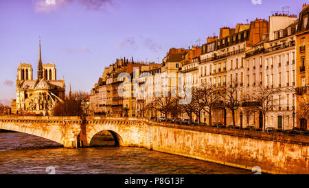 Paris Notre Dame bei Sonnenaufgang ist in goldenes Licht getaucht. Gebäude und eine Brücke über die Seine auch mit schönen, warmen Farben. Pastell violett Himmel. Stockfoto