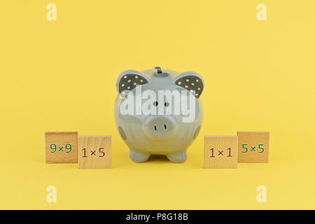 Lustige grau Sparschwein auf gelbem Hintergrund mit Holz- Tablet mit Zahlen. Studie der Multiplikation im Brettspiel, zurück zu Schule Konzept Stockfoto
