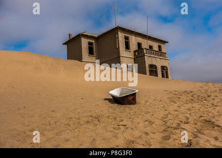 Verlassene Gebäude in Ghost Town von ehemaligen Diamond mining Gemeinschaft von Kolmanskop, die in der Nähe von Lüderitz in der Namib Wüste Namibias mit altem Email Badewanne Stockfoto