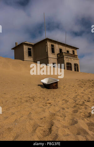 Verlassene Gebäude in Ghost Town von ehemaligen Diamond mining Gemeinschaft von Kolmanskop, die in der Nähe von Lüderitz in der Namib Wüste Namibias mit altem Email Badewanne Stockfoto