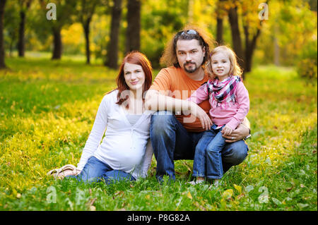 Schöne erwartet Familie im Herbst Park bei Sonnenuntergang Stockfoto