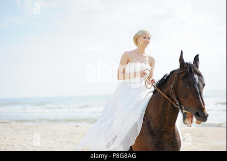 Hochzeit am Strand: Braut auf einem Pferd durch das Meer Stockfoto