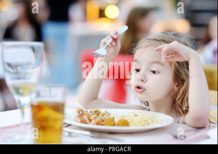 Süße kleine Mädchen isst Spaghetti im Freien Stockfoto