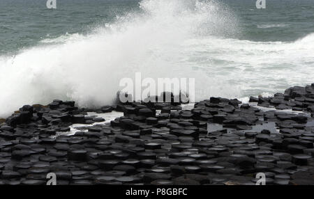 Wellen brechen im vieleckigen Basaltsäulen Giant's Causeway. Bushmills, County Antrim, Nordirland, Großbritannien. Stockfoto