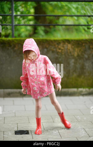 Adorable kleine Mädchen im regen Stiefel in einem Pudel stehend Stockfoto