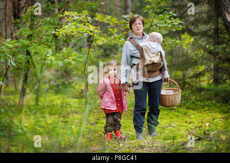 Großmutter und ihre Mädchen Pilze sammeln im Wald Stockfoto