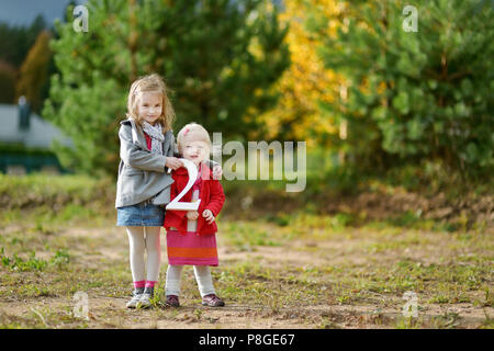 Zwei Entzückende kleine Schwestern halten die beiden großen Anzahl Stockfoto