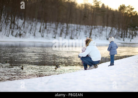 Vater und seine Töchter feeding ducks im Winter Stockfoto