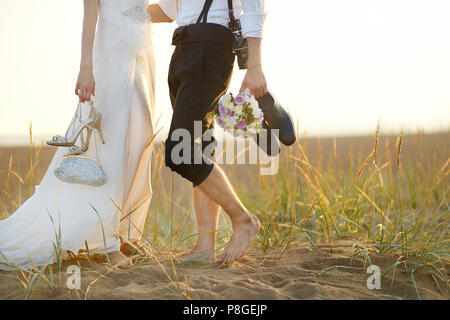 Glückliche Braut und Bräutigam am schönen Strand bei Sonnenuntergang Stockfoto