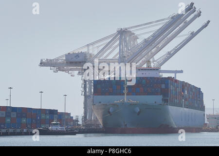 Die riesigen COSCO Container schiff, COSCO PORTUGAL, festgemacht am Pier J In der Long Beach Container Terminal, Kalifornien, USA. AmNav Schlepper durch den Bogen. Stockfoto