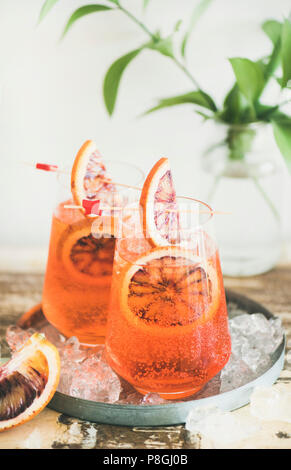 Italienische Aperol Spritz Alkohol Cocktail mit Eis und Blut Orangenscheiben auf Tisch, vertikale Komposition. Traditionelle Aperol Spritz Cocktail. Sommer Ref. Stockfoto